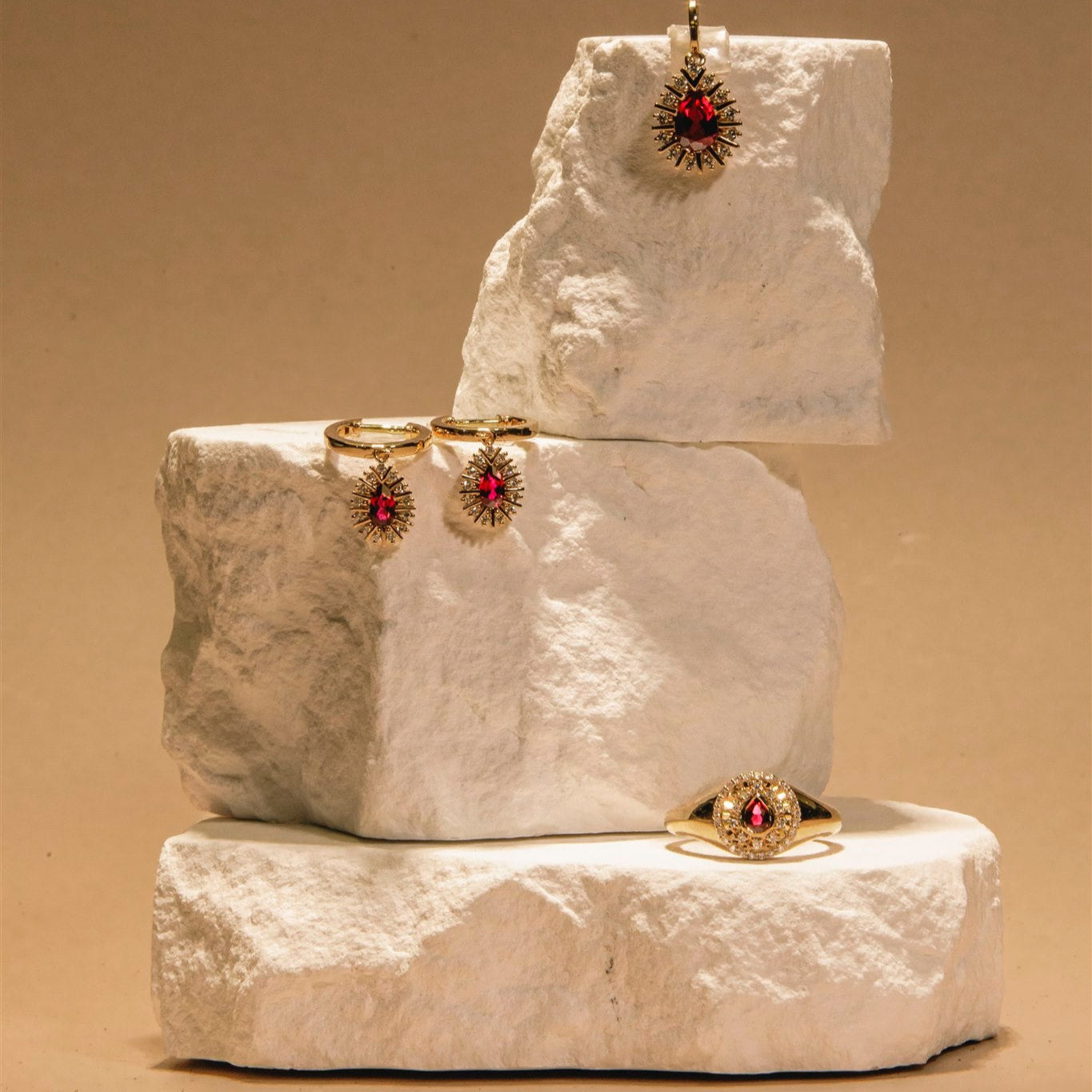 White stone jewelry display with earrings and rings on a beige background