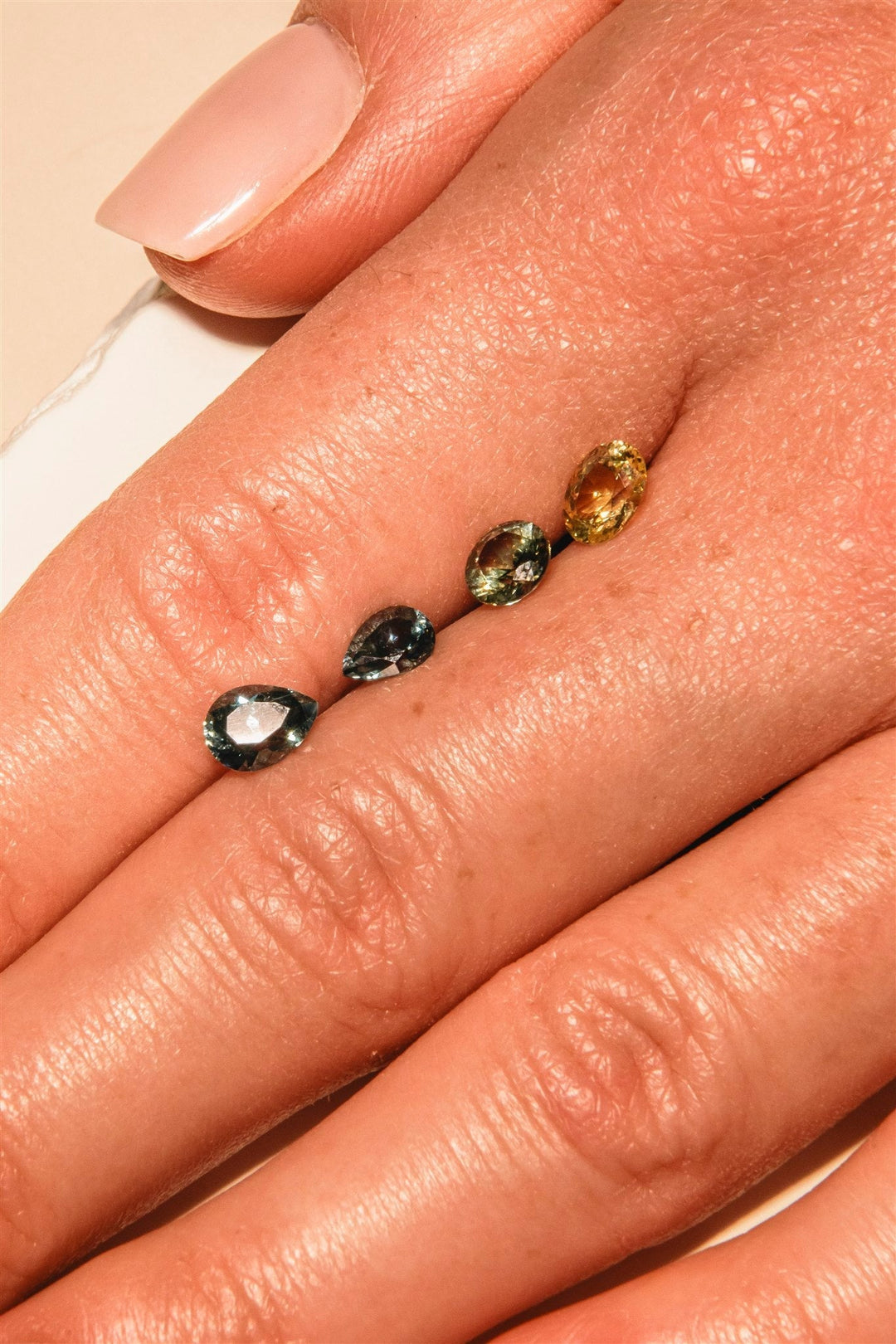 Montana sapphires in teal, green, blue, and golden colors held in the hand
