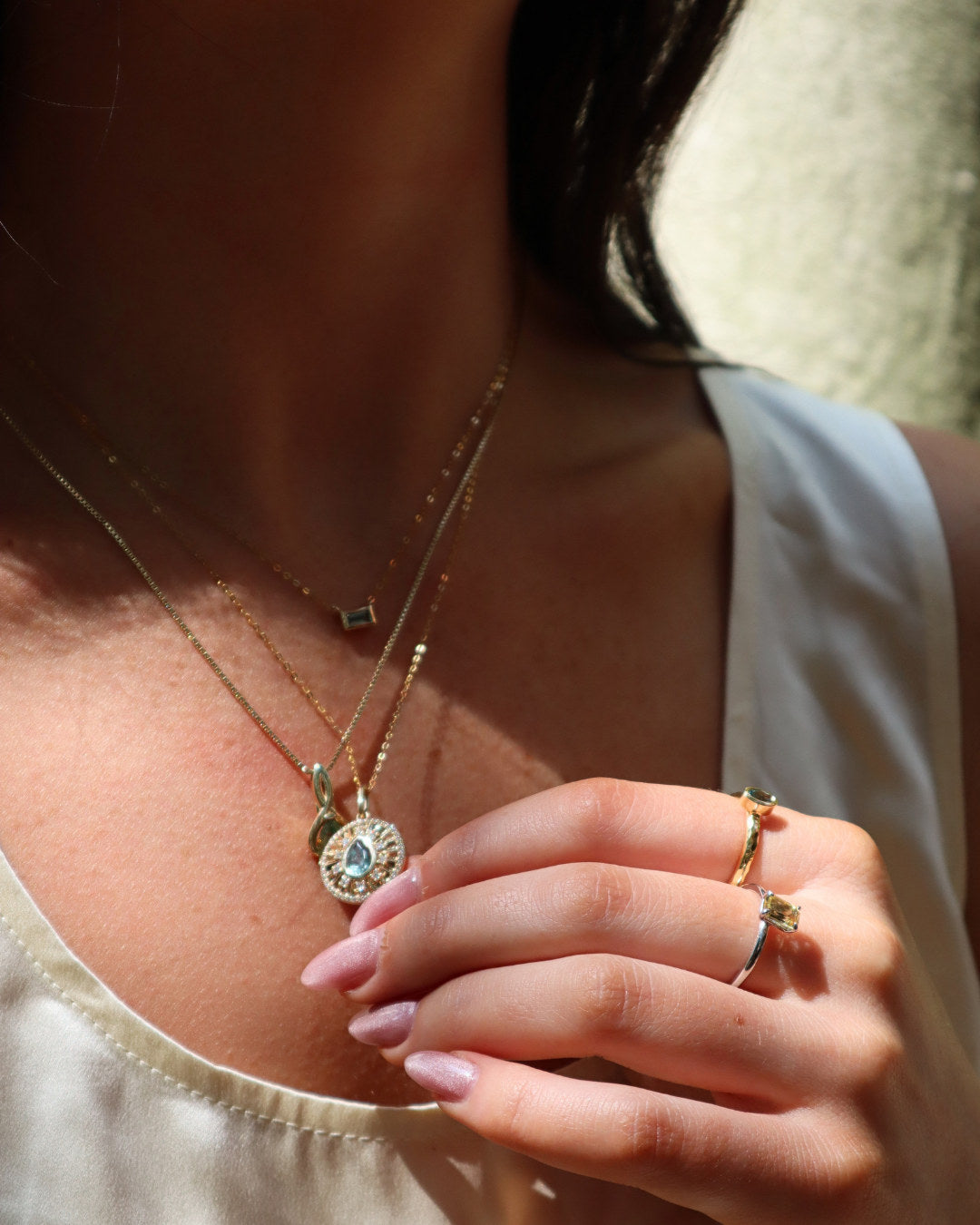 Three Talismania necklaces worn layered — the Big Sky Baguette Necklace, the Vela Pendant and the Flow Pendant — with name labels — Talismania