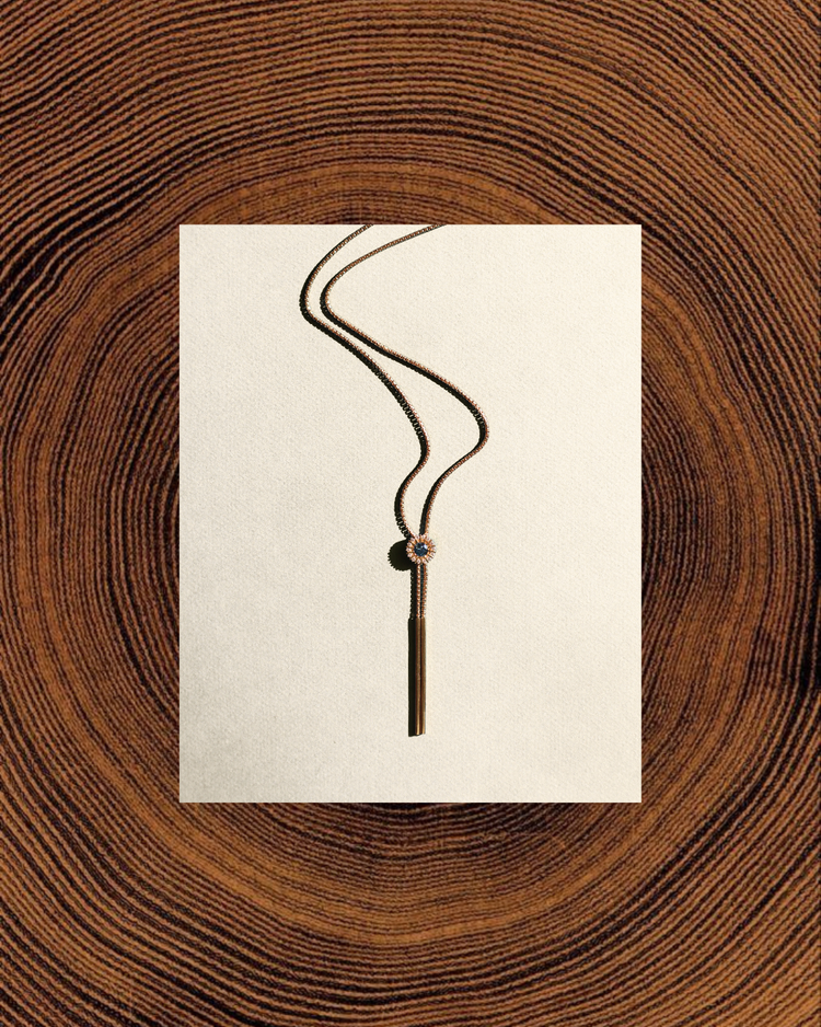 A Headwaters bolo necklace laid on a paper card over end-grain timber