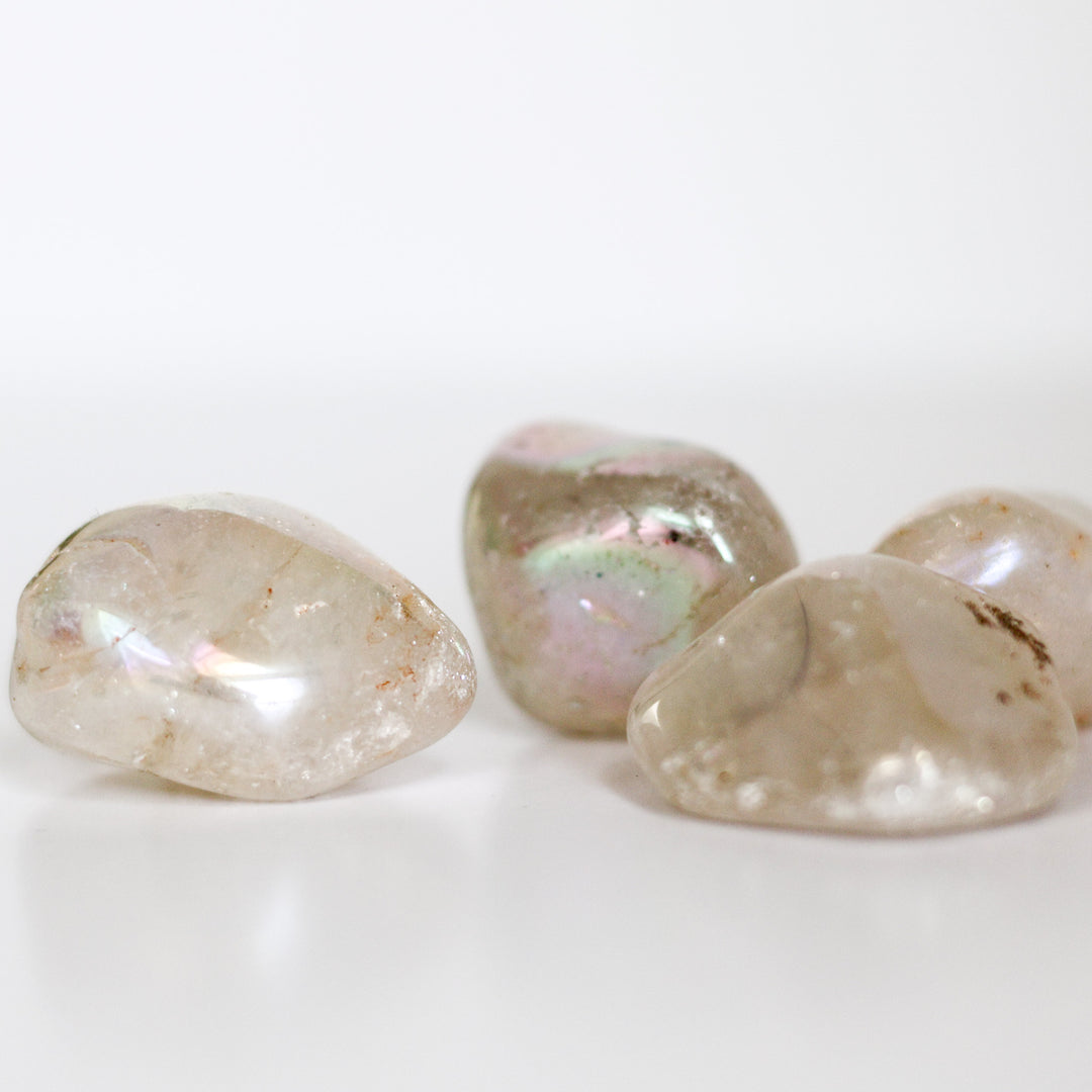 A collection of polished Angel Aura Quartz tumblestones with a milky appearance and iridescent rainbow effect.