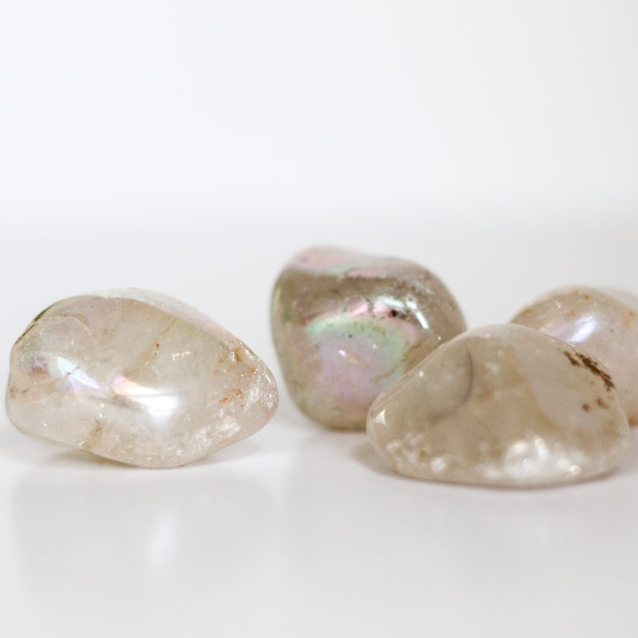 A collection of polished Angel Aura Quartz tumblestones with a milky appearance and iridescent rainbow effect.
