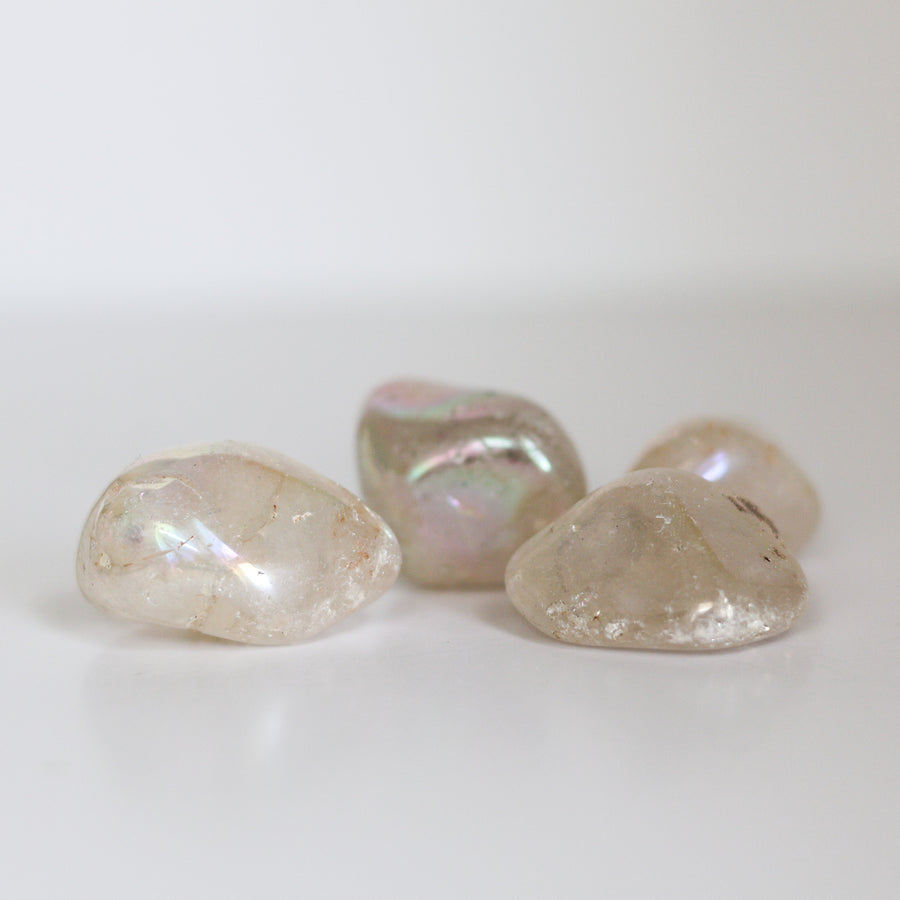 A collection of polished Angel Aura Quartz tumblestones with a milky appearance and iridescent rainbow effect.