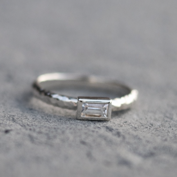 Silver ring with a rectangular diamond on a textured gray surface
