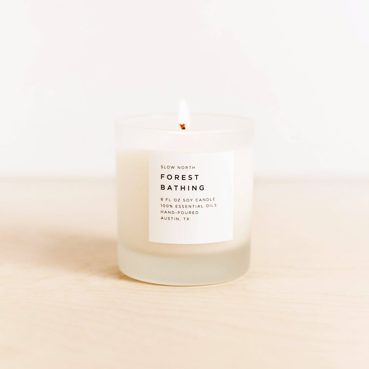 Candle labeled 'Forest Bathing' by Slow North on a light pink background