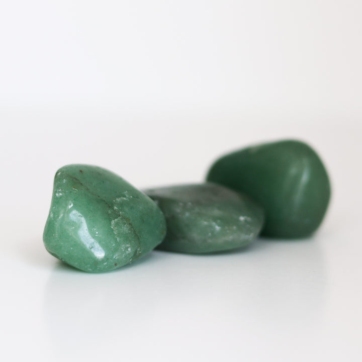 Three polished Green Aventurine tumblestones arranged on a white surface.