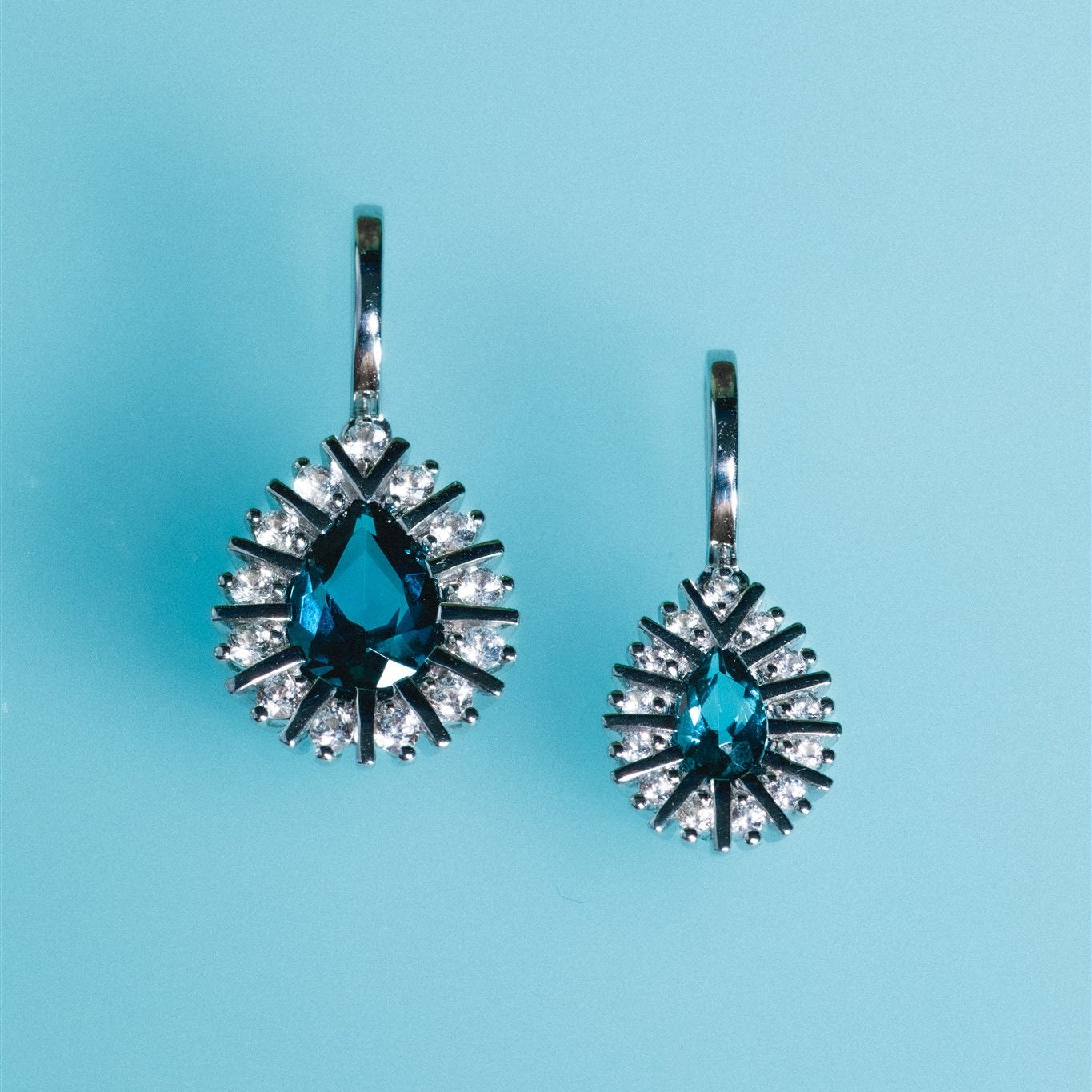 Pair of earrings with blue gemstones on a light blue background