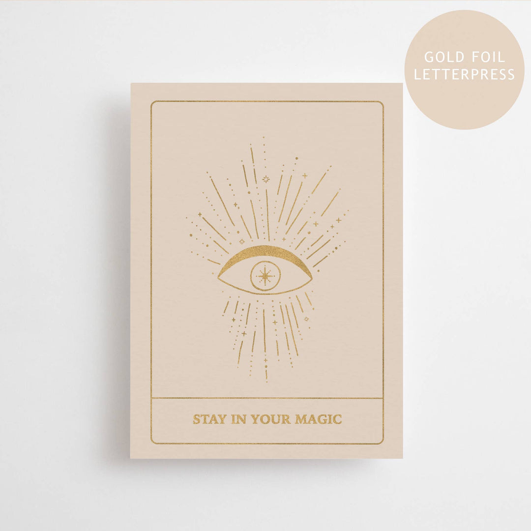Beige card with gold foil eye design and 'Stay in Your Magic' text on a white background