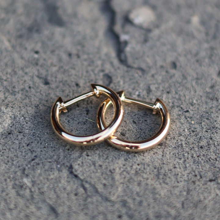 Gold hoop earrings on a textured gray surface