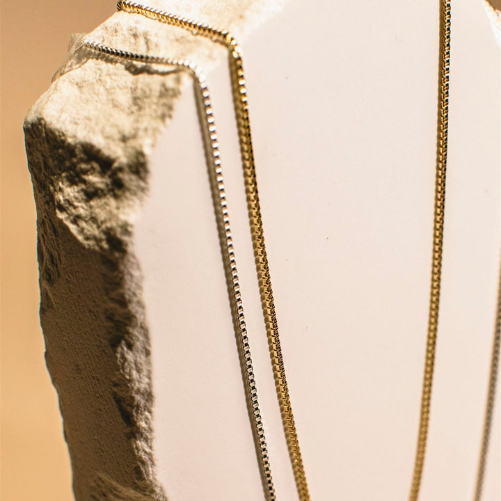 Gold chain on a white cushion with a beige background