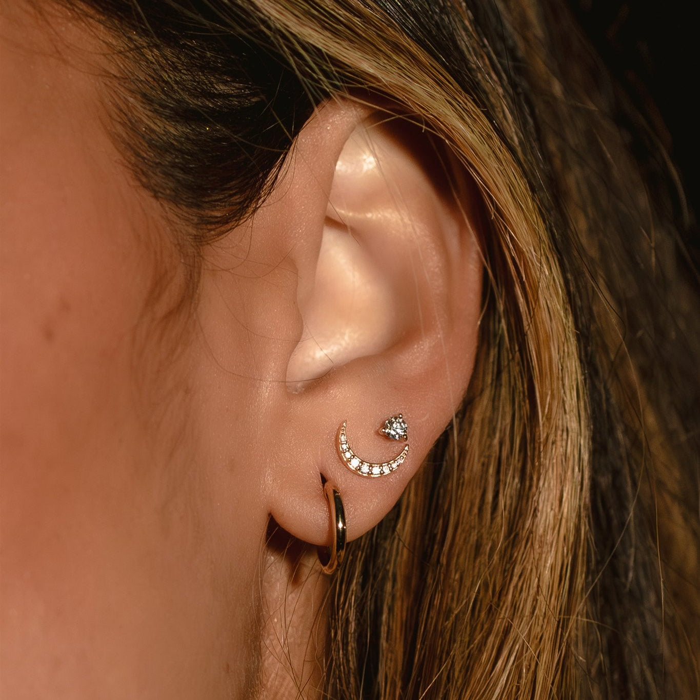 Close-up of an ear with earrings against a dark background