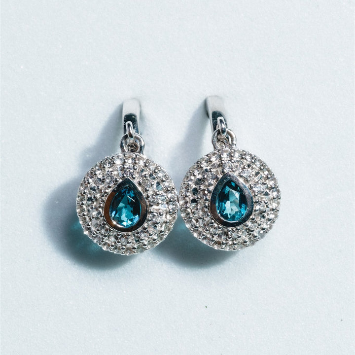 Pair of silver earrings with blue gemstones on a light gray background