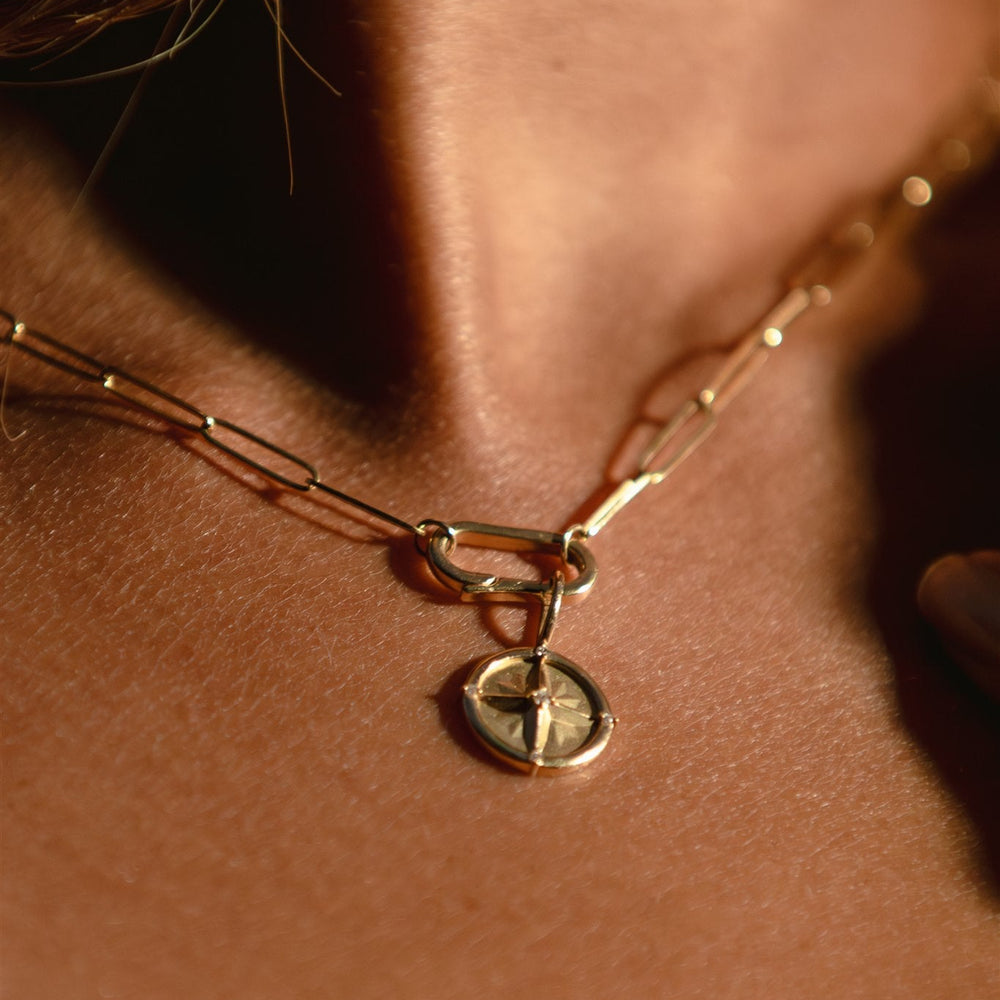 Close-up of a gold necklace with a pendant on a person's neck.