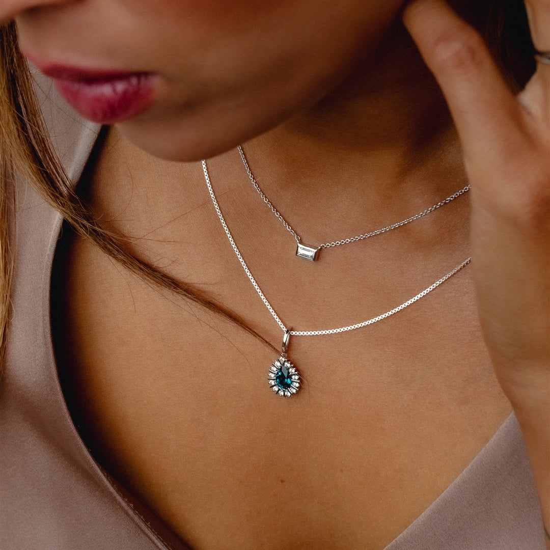 Close-up of a woman wearing a necklace with a blue pendant.