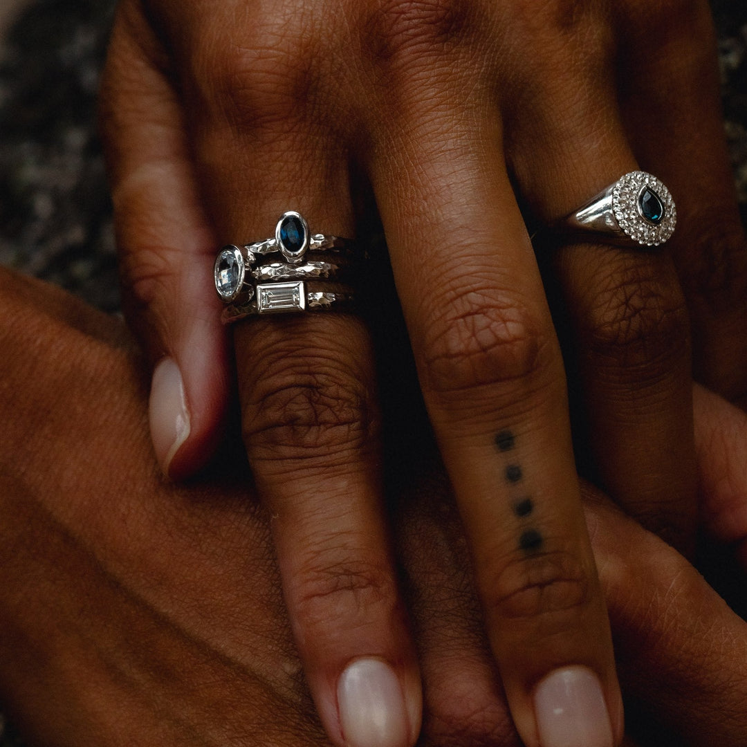 Close-up of a hand wearing multiple silver rings with gemstones on a blurred background