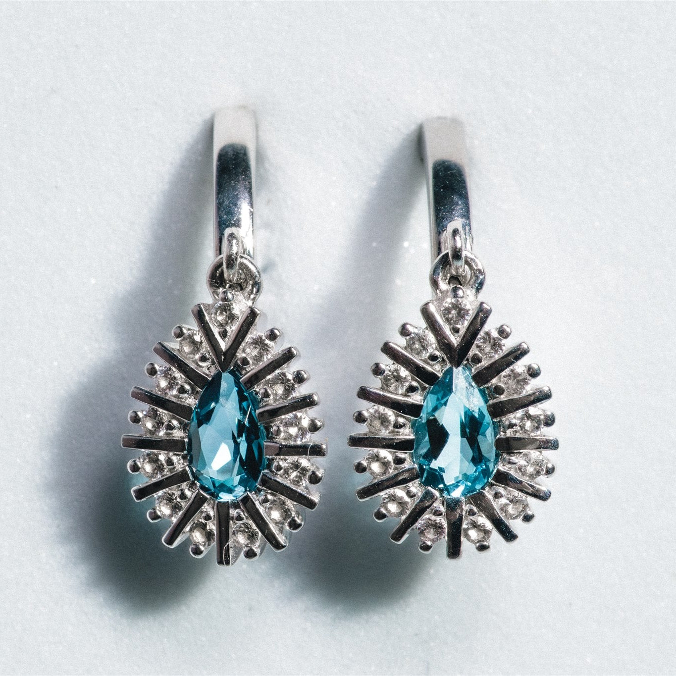 Pair of silver earrings with blue gemstones on a light gray background