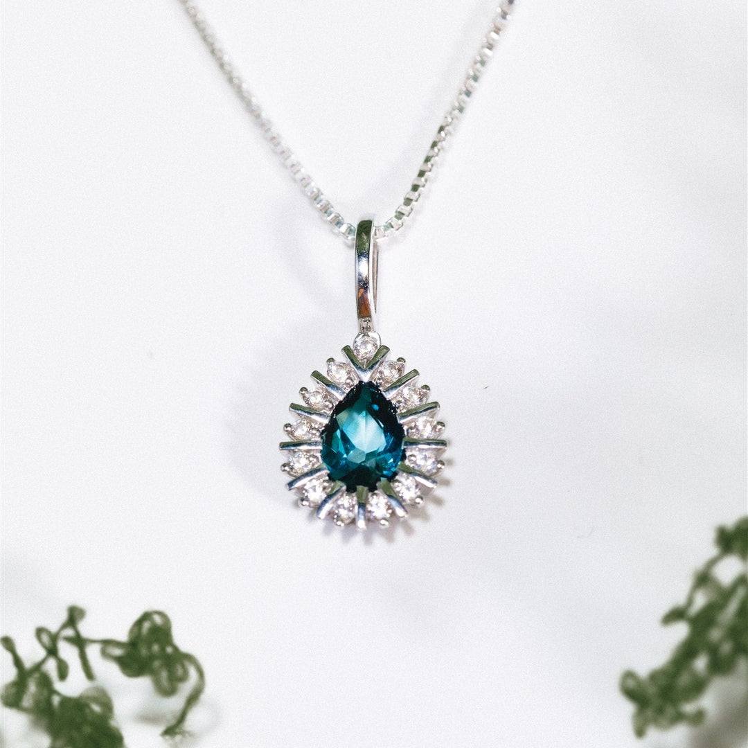 Silver necklace with a blue gemstone pendant on a white background