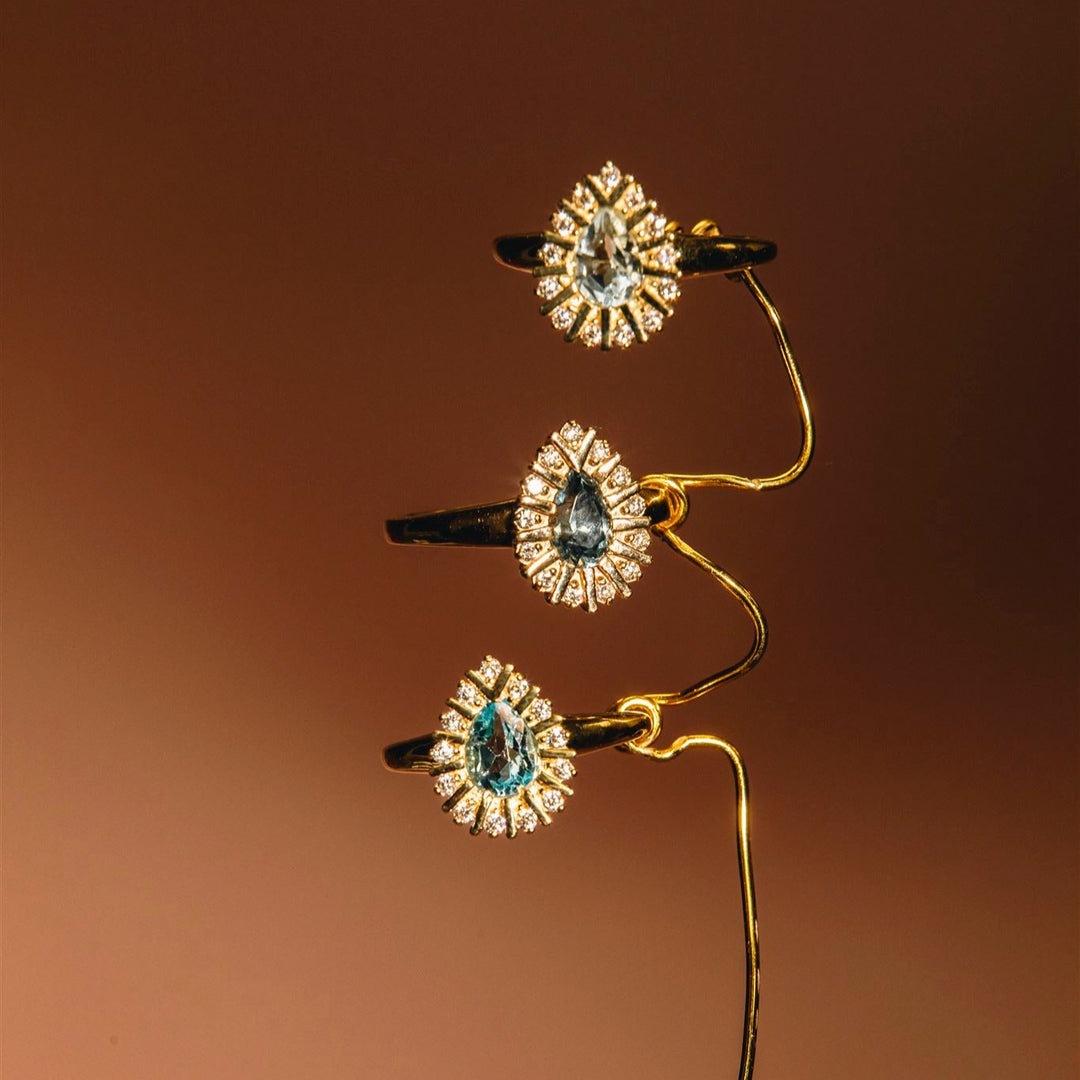 Set of three gold hair clips with gemstone-like decorations on a brown background