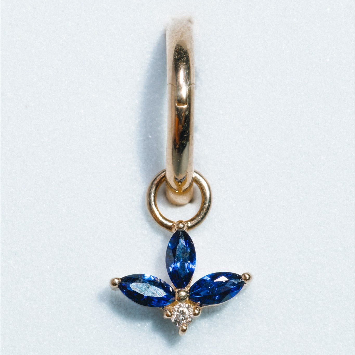 Gold earring with blue gemstones on a white background