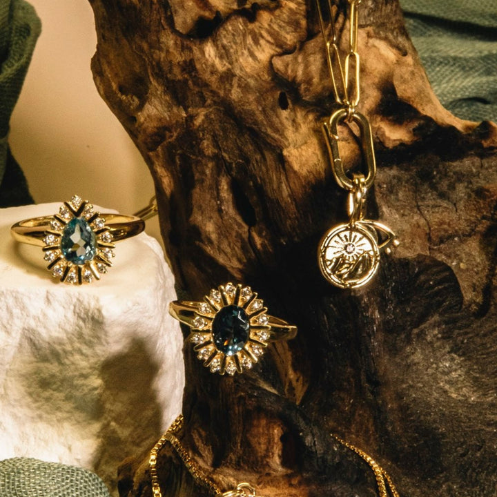 Jewelry set including ring, earrings, and necklace on a textured surface with green fabric.