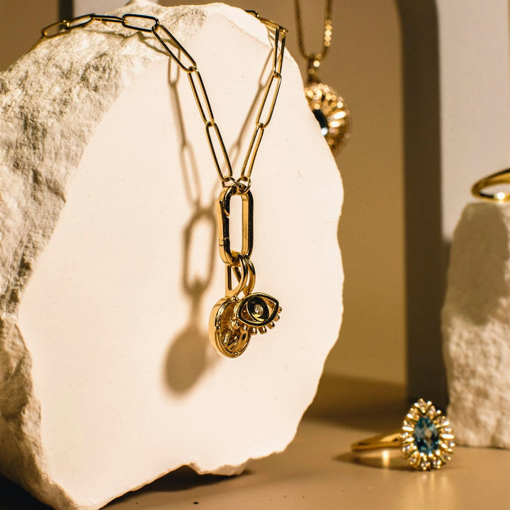 Gold jewelry with pendants on a textured white surface