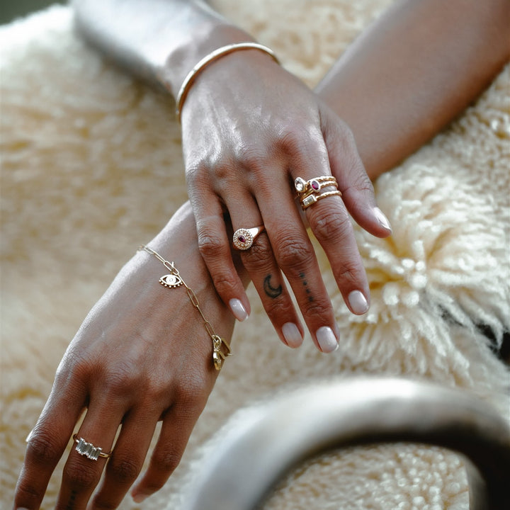 Close-up of hands with gold jewelry on a textured surface