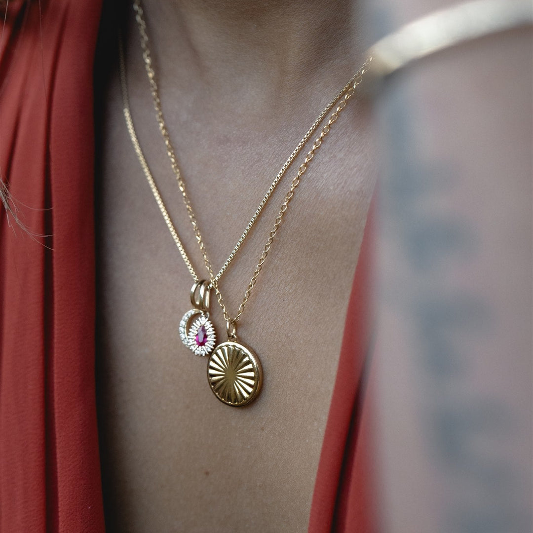 Gold necklace with pendants on a person wearing a red garment