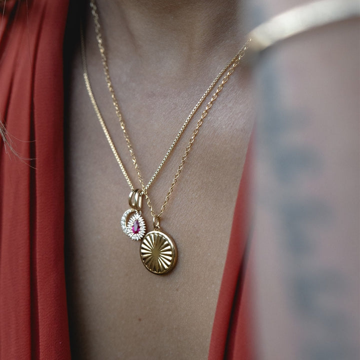 Gold necklace with pendants on a person wearing a red garment
