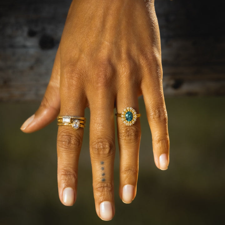 Hand wearing two gold rings with gemstones on a blurred background