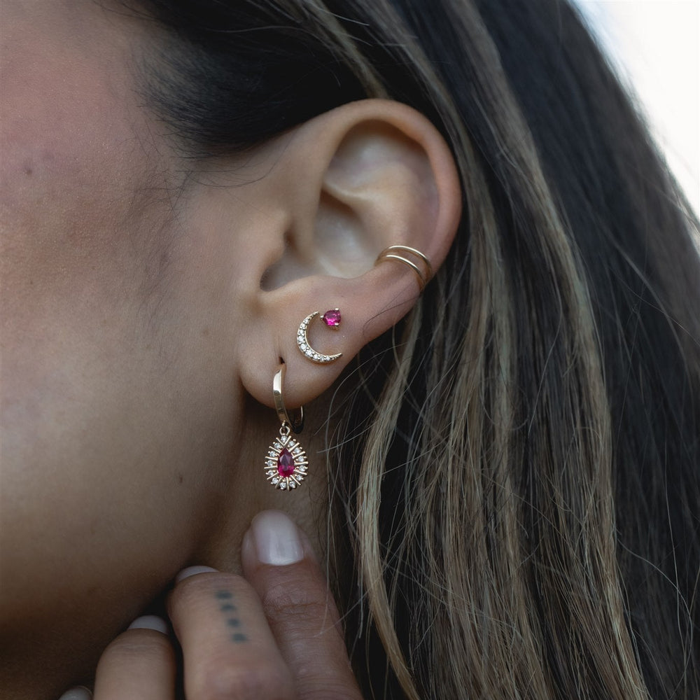Close-up of an ear with multiple gold and gemstone earrings.