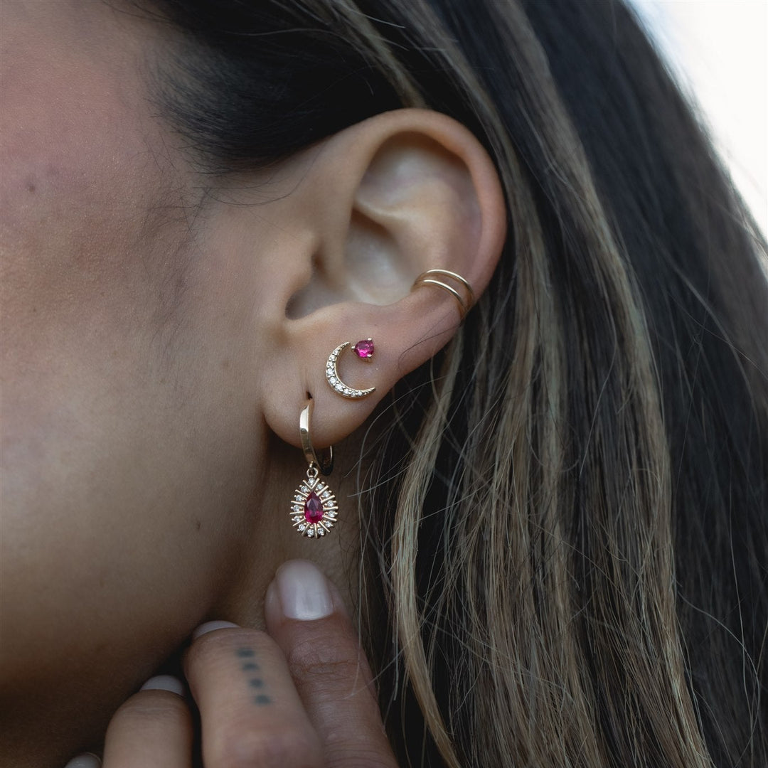 Close-up of an ear with multiple gold and gemstone earrings.