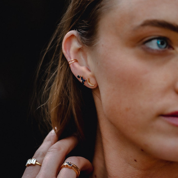 Close-up of a woman's ear with gold earrings and rings.