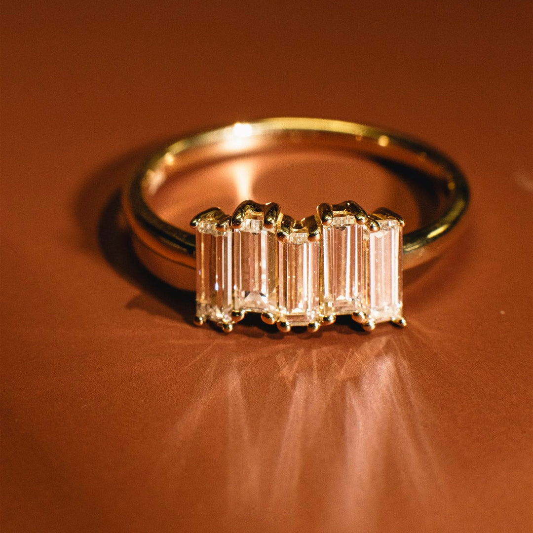 Gold ring with baguette-cut diamonds on a brown background