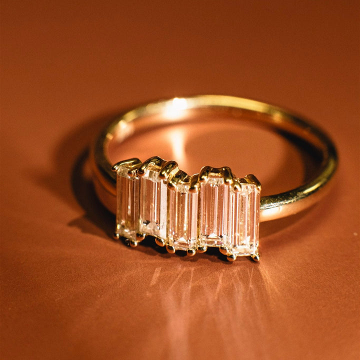 Gold ring with emerald-cut diamond on a brown background