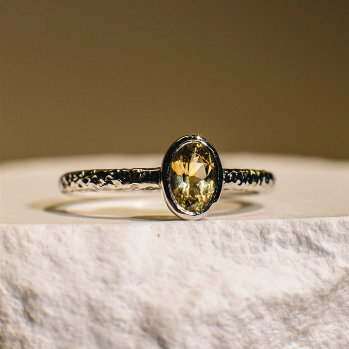 Ring with a yellow gemstone on a marble surface