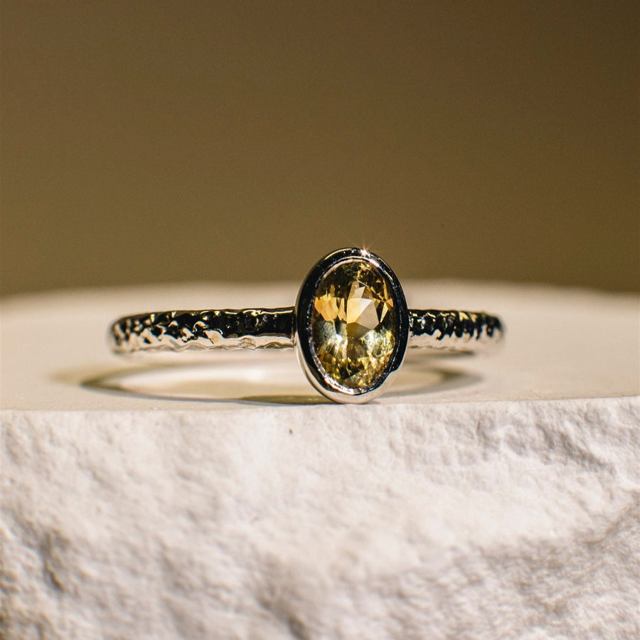 Ring with a yellow gemstone on a marble surface