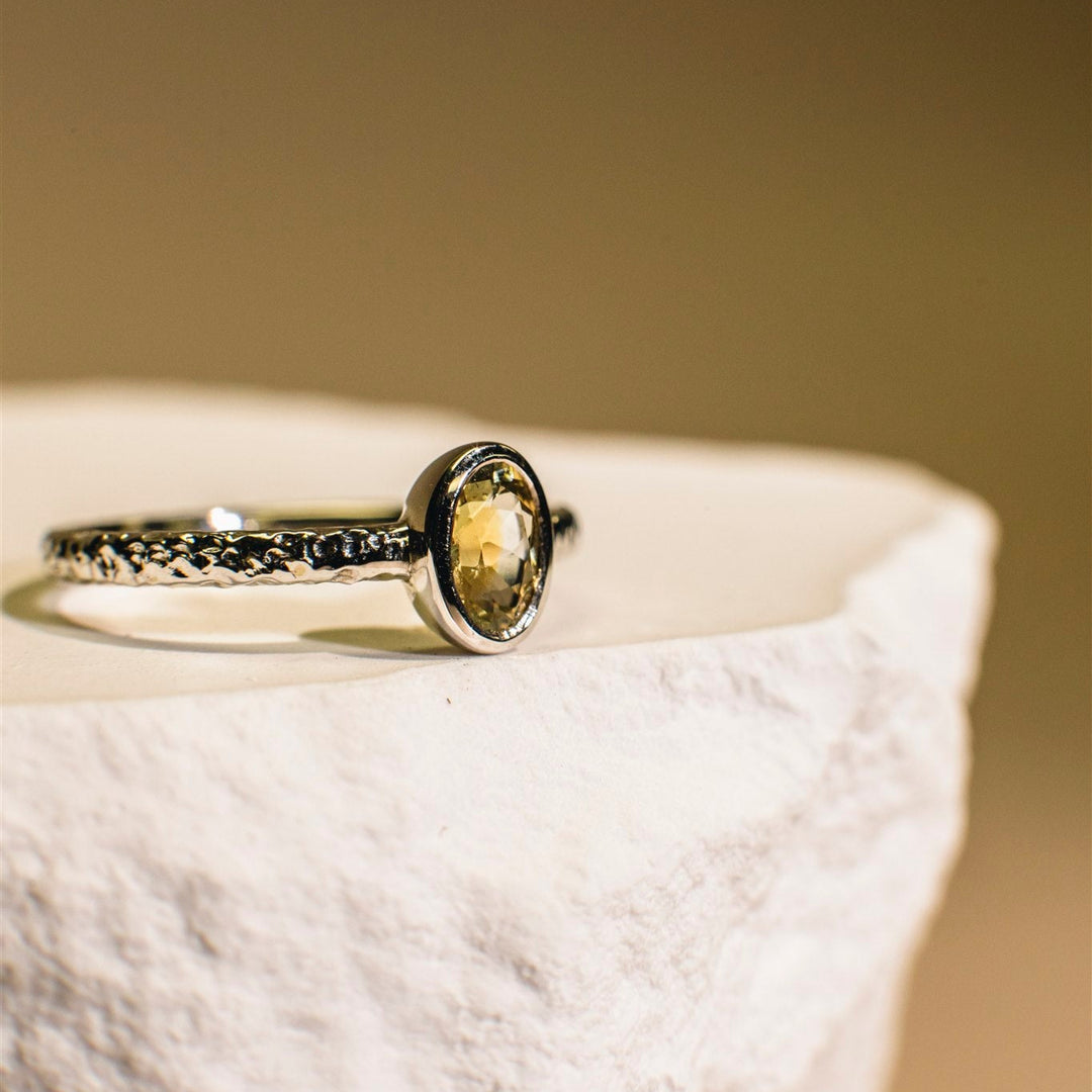 Ring with a yellow gemstone on a textured surface