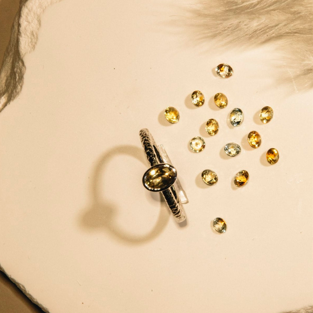 Gold ring with scattered gemstones on a textured beige surface