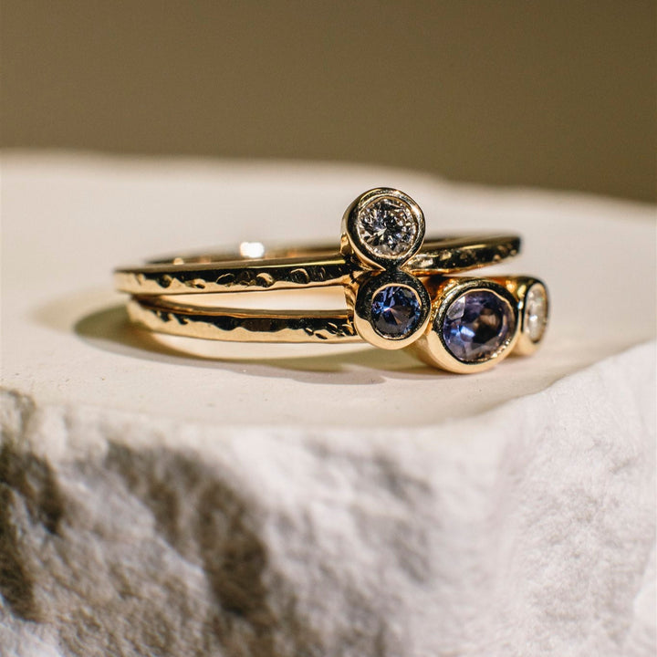 Gold ring with embedded gemstones on a textured surface