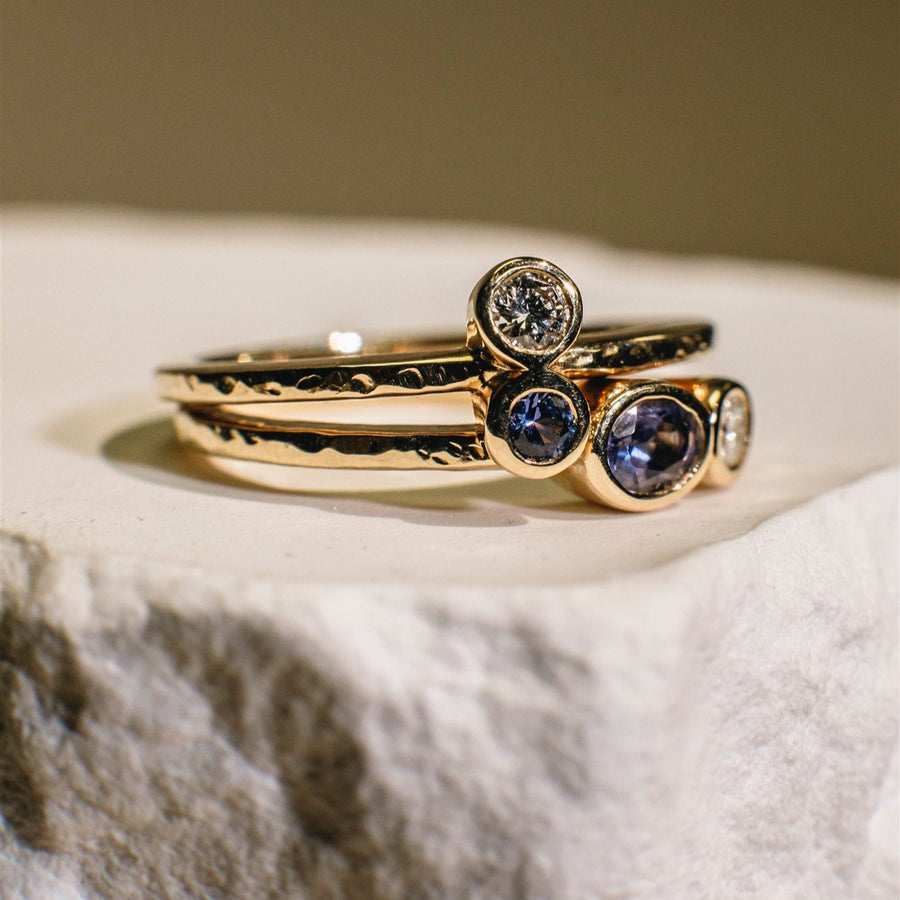 Gold ring with embedded gemstones on a textured surface