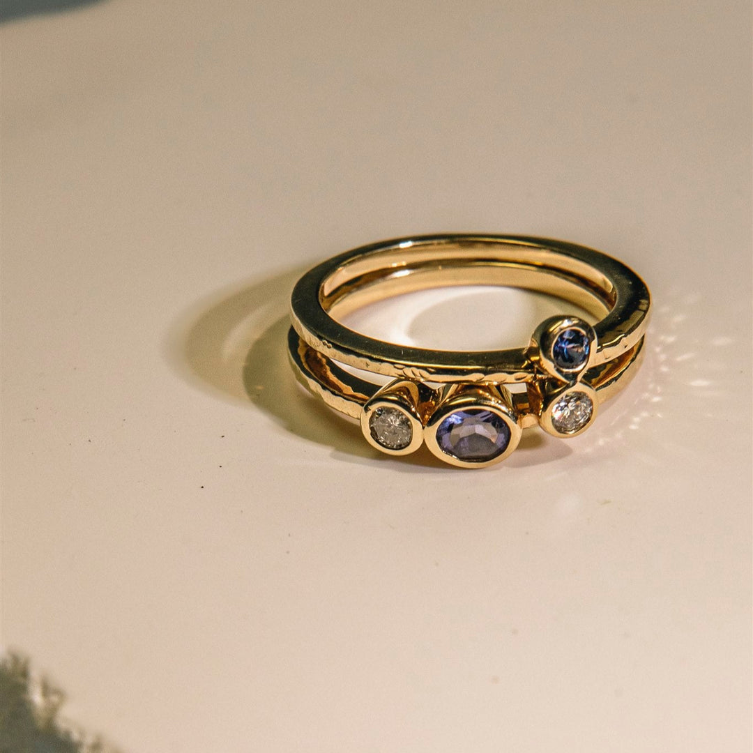 Gold ring with gemstones on a textured beige surface