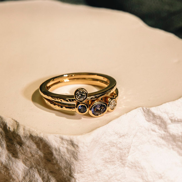 Gold ring with embedded stones on a textured surface