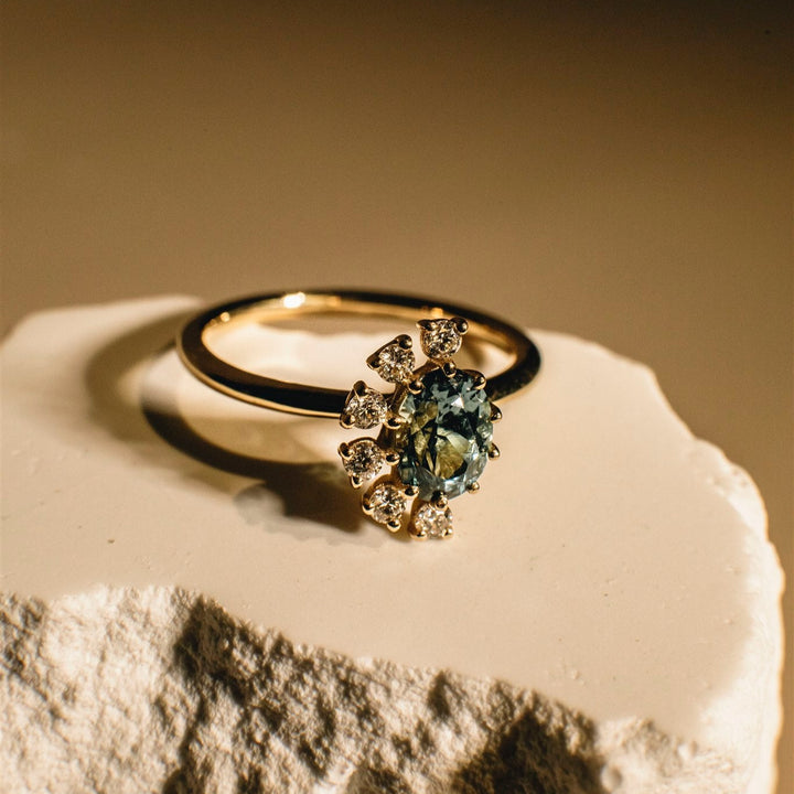 Gold ring with a green gemstone on a textured surface