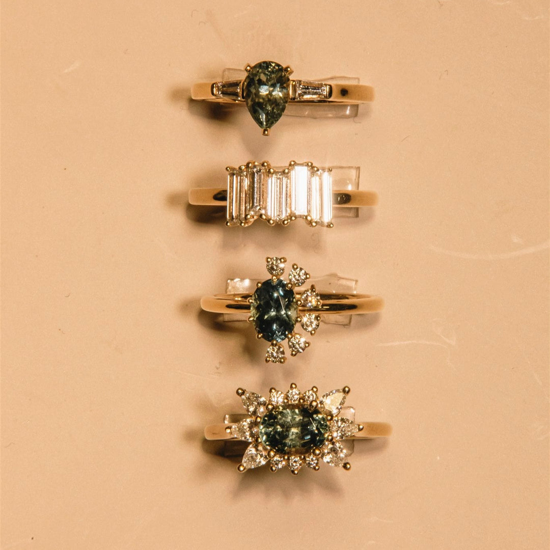 Four gold rings with gemstones on a beige background