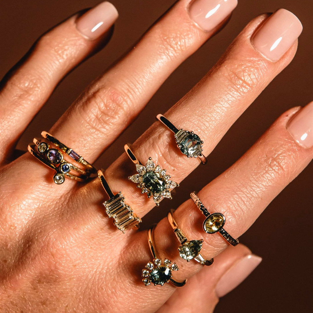 Hand wearing multiple rings with gemstones on a dark background