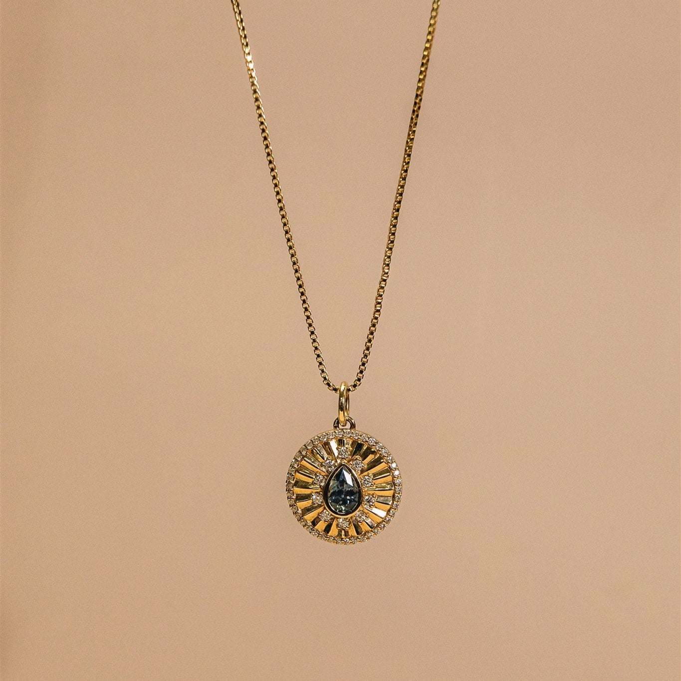 Gold necklace with a circular pendant on a beige background