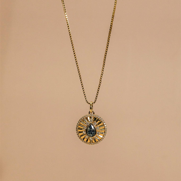 Gold necklace with a circular pendant on a beige background