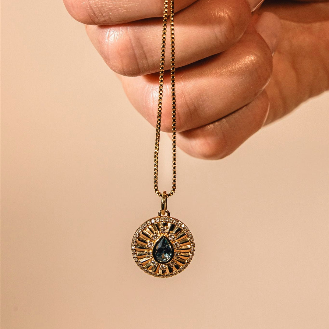Jewelry stand with necklace and ring on a stone base against a beige background