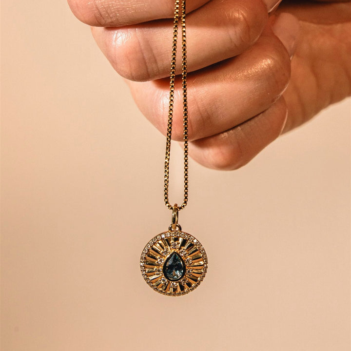 Jewelry stand with necklace and ring on a stone base against a beige background