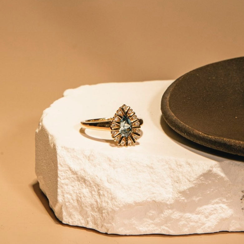 Gold ring with a star-like design on a textured white surface with a brown background